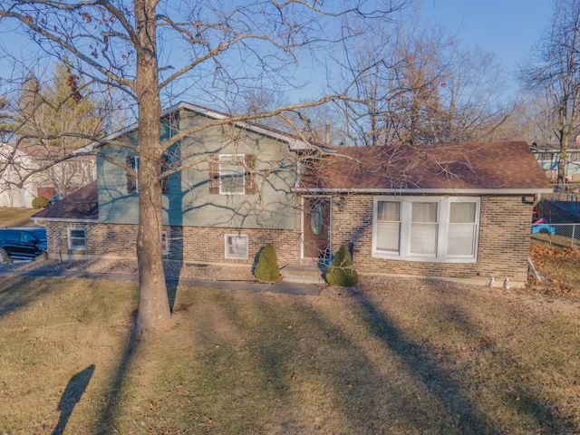 split level home featuring brick siding, a front yard, and fence