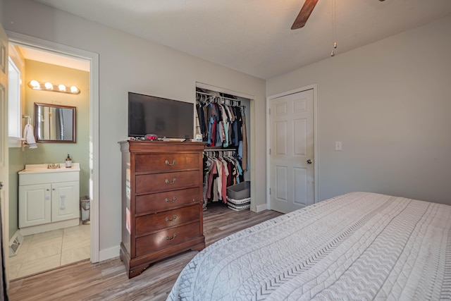 bedroom featuring a closet, baseboards, ensuite bath, and wood finished floors