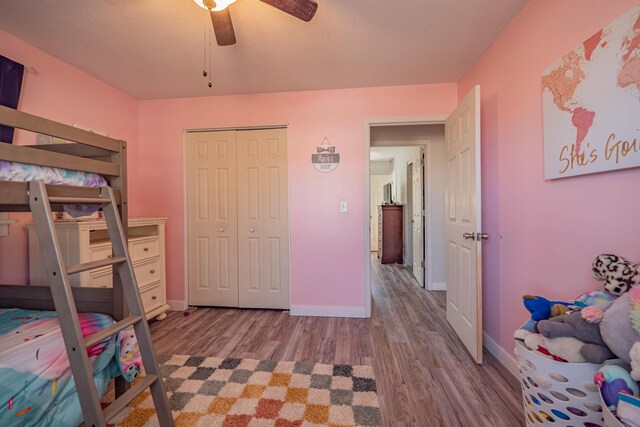 bedroom featuring a ceiling fan, wood finished floors, baseboards, and a closet