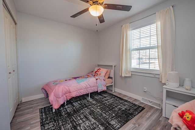 bedroom featuring a closet, ceiling fan, baseboards, and wood finished floors