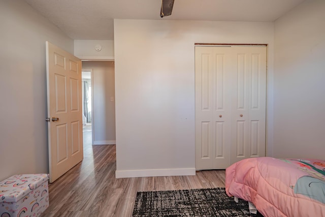 bedroom with a closet, baseboards, and light wood-style flooring