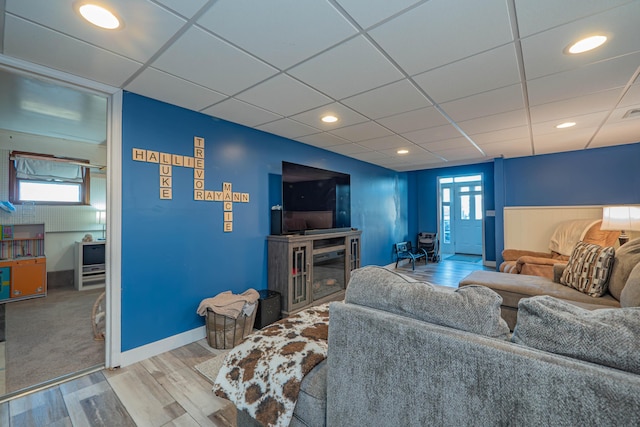 living room with a drop ceiling, recessed lighting, baseboards, and wood finished floors