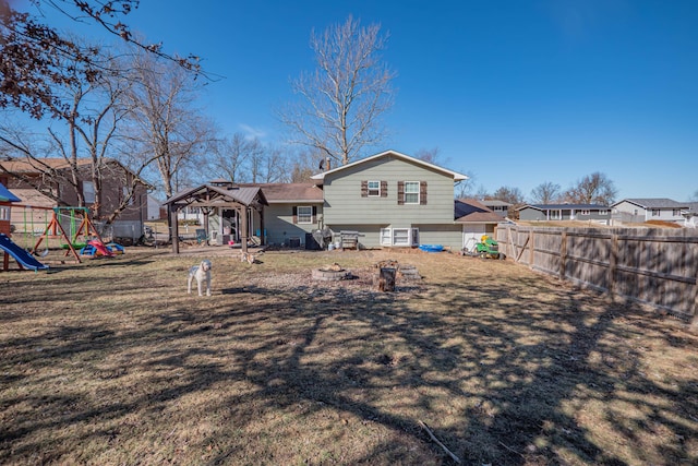 rear view of property with a playground, a yard, a fenced backyard, and a residential view