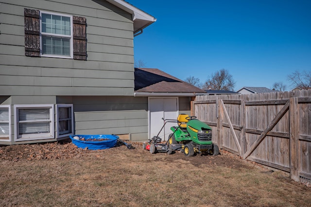 view of side of property with a yard, a shingled roof, and fence