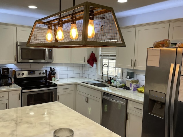 kitchen with decorative backsplash, white cabinetry, stainless steel appliances, and a sink