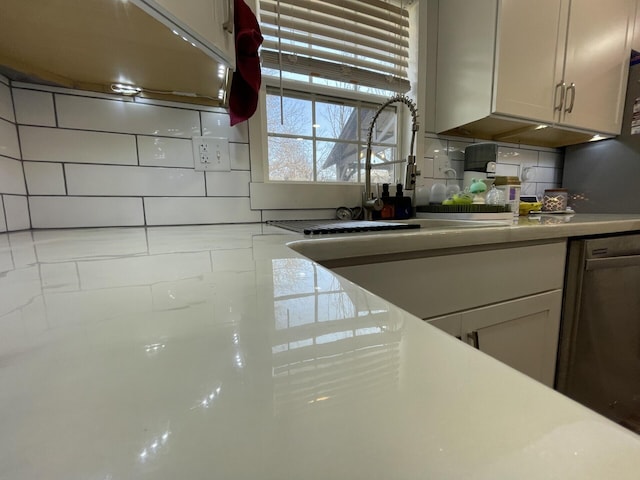 kitchen with a sink, tasteful backsplash, stainless steel dishwasher, and light countertops