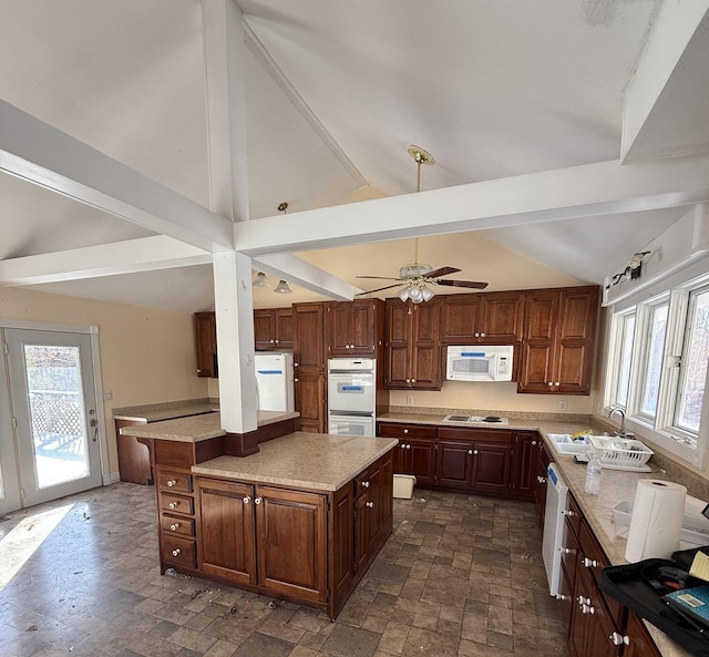 kitchen with vaulted ceiling with beams, stone finish flooring, a sink, ceiling fan, and white appliances