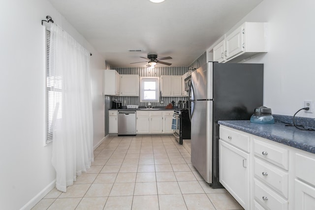 kitchen with light tile patterned floors, stainless steel appliances, a ceiling fan, white cabinets, and dark countertops