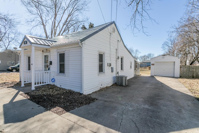 view of front facade with driveway, a detached garage, metal roof, cooling unit, and an outdoor structure