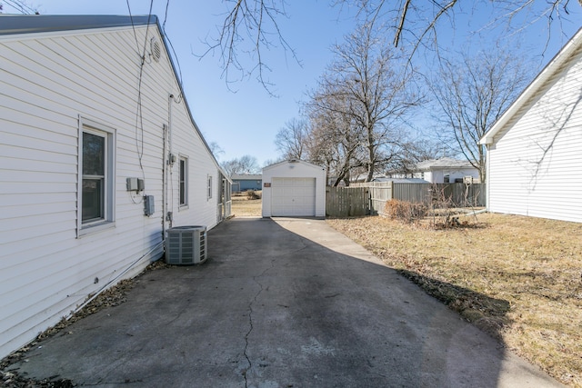 view of home's exterior featuring an outbuilding, aphalt driveway, central air condition unit, a detached garage, and fence