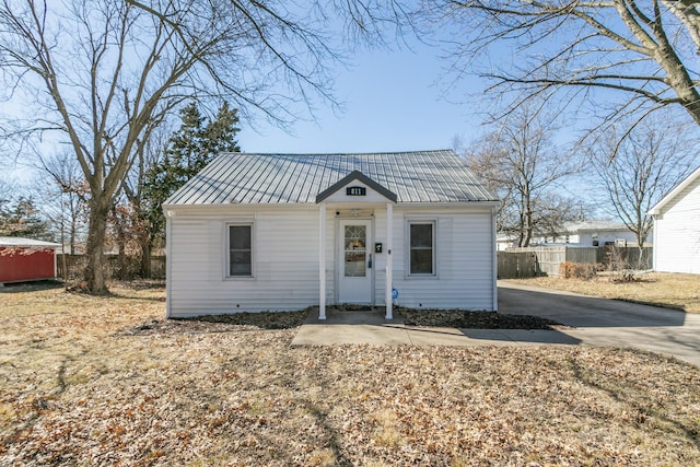 bungalow-style house with driveway, fence, and metal roof