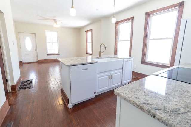 kitchen featuring visible vents, dishwasher, dark wood-style flooring, hanging light fixtures, and a sink