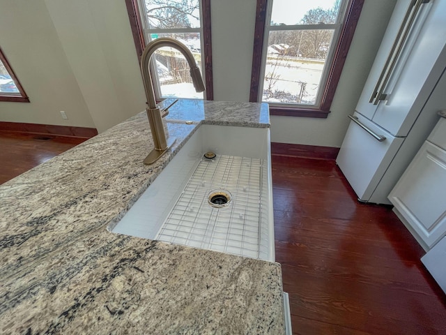 details with freestanding refrigerator, dark wood-style flooring, a sink, and baseboards