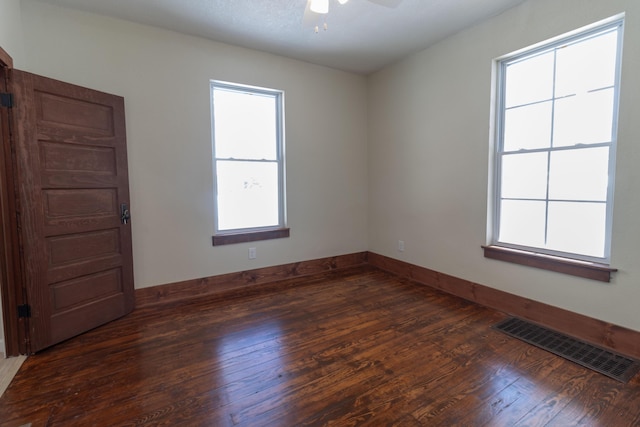 spare room with a ceiling fan, wood-type flooring, visible vents, and baseboards