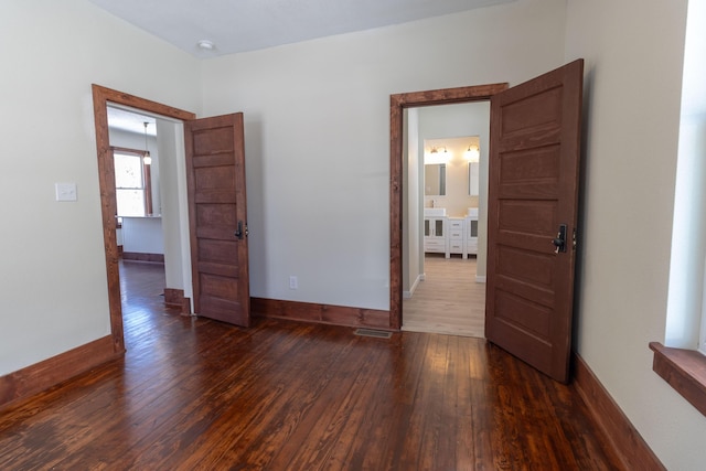 unfurnished room with visible vents, baseboards, and dark wood-type flooring