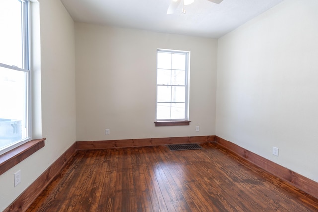 unfurnished room with ceiling fan, dark wood finished floors, visible vents, and baseboards