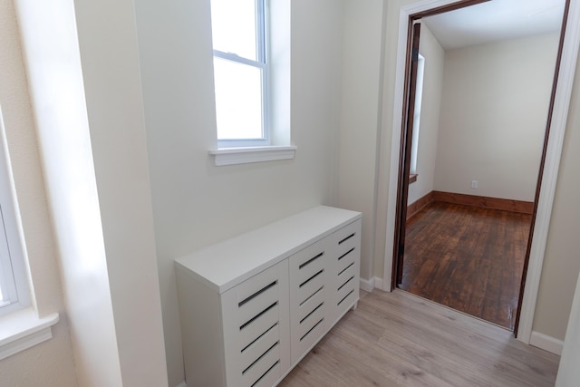 corridor with light wood-type flooring and baseboards