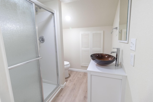 bathroom with toilet, a stall shower, vanity, wood finished floors, and baseboards