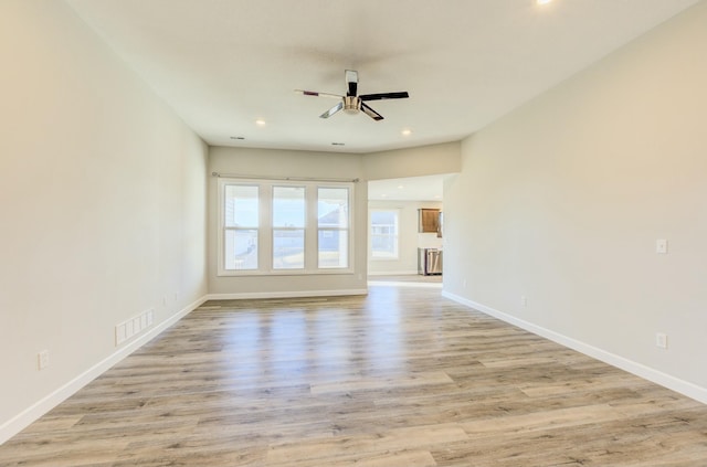 unfurnished living room with visible vents, ceiling fan, light wood-style flooring, and baseboards