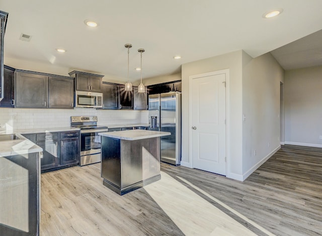 kitchen with tasteful backsplash, a center island, light stone countertops, stainless steel appliances, and pendant lighting