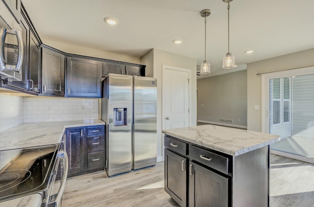 kitchen featuring a kitchen island, appliances with stainless steel finishes, light stone counters, light wood-style floors, and pendant lighting