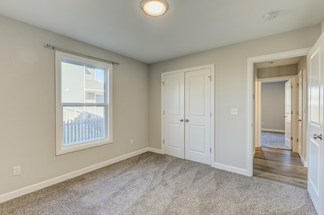 unfurnished bedroom with carpet floors, a closet, and baseboards