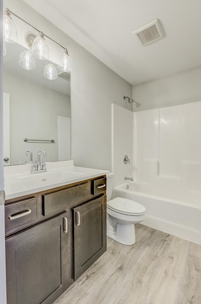 bathroom featuring toilet, visible vents, shower / washtub combination, and wood finished floors