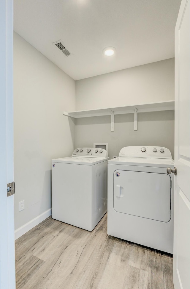 washroom with laundry area, separate washer and dryer, visible vents, and light wood-style floors