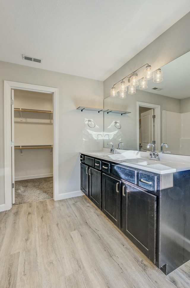 bathroom with wood finished floors, visible vents, a spacious closet, and double vanity