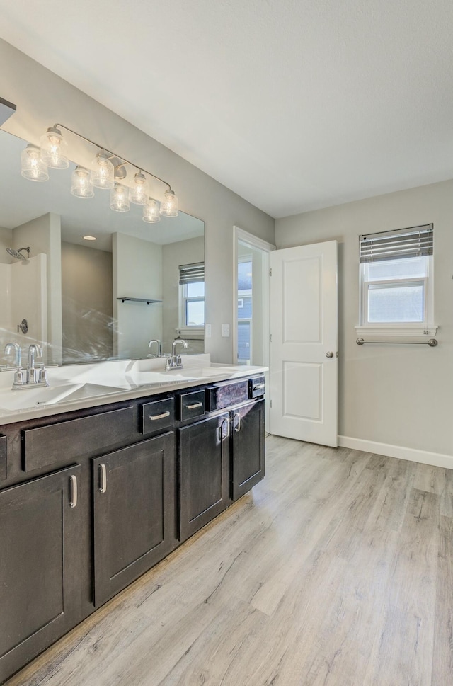 full bath featuring double vanity, a healthy amount of sunlight, a sink, and wood finished floors