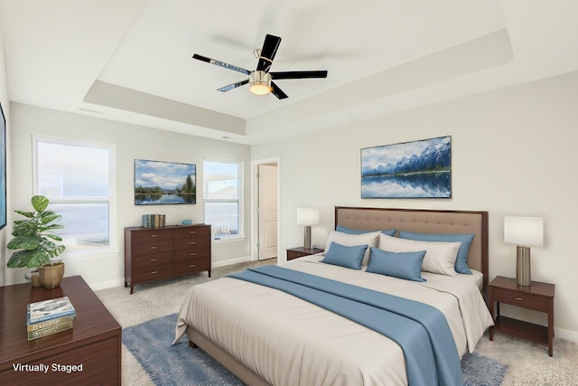 bedroom with a tray ceiling, light carpet, and baseboards