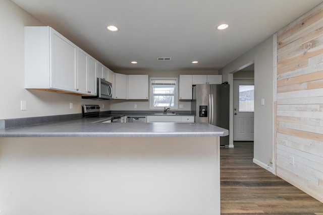 kitchen featuring a peninsula, appliances with stainless steel finishes, a sink, and white cabinetry