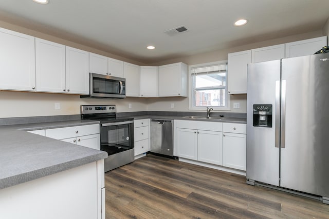 kitchen featuring visible vents, dark wood-style floors, stainless steel appliances, white cabinetry, and a sink