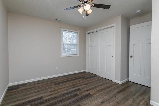 unfurnished bedroom featuring dark wood finished floors, a closet, visible vents, a ceiling fan, and baseboards