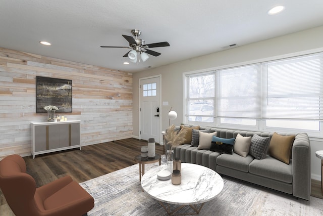 living room featuring recessed lighting, dark wood-type flooring, an accent wall, ceiling fan, and wooden walls