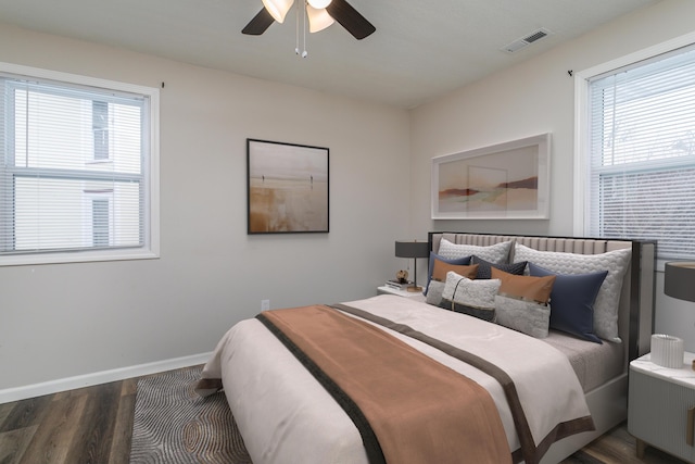 bedroom with visible vents, dark wood finished floors, baseboards, and multiple windows