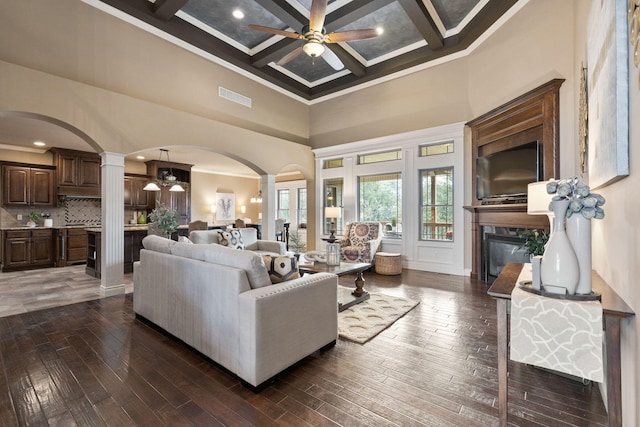 living area with visible vents, coffered ceiling, a ceiling fan, a glass covered fireplace, and dark wood-type flooring