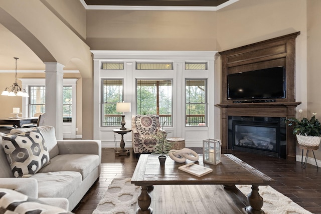 living area with baseboards, dark wood finished floors, a glass covered fireplace, crown molding, and ornate columns