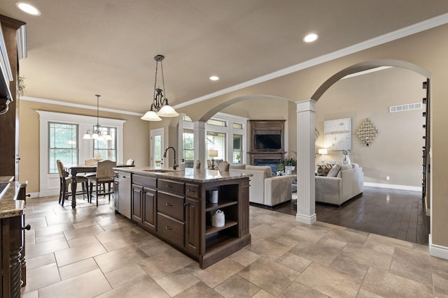 kitchen with visible vents, stainless steel dishwasher, a sink, dark brown cabinets, and light stone countertops