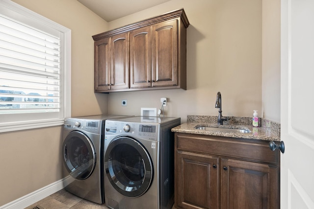 laundry area featuring cabinet space, baseboards, a sink, and washing machine and clothes dryer