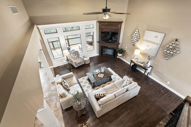 living area with ceiling fan, a fireplace, wood finished floors, visible vents, and baseboards