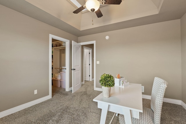 carpeted home office with ceiling fan, a raised ceiling, and baseboards