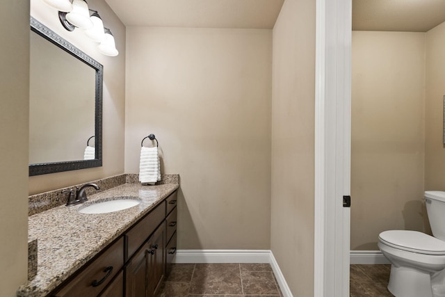 bathroom with baseboards, vanity, and toilet