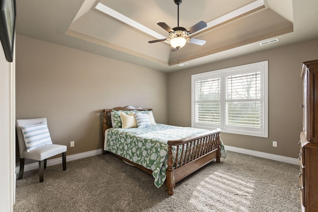 carpeted bedroom with ceiling fan, baseboards, visible vents, and a raised ceiling