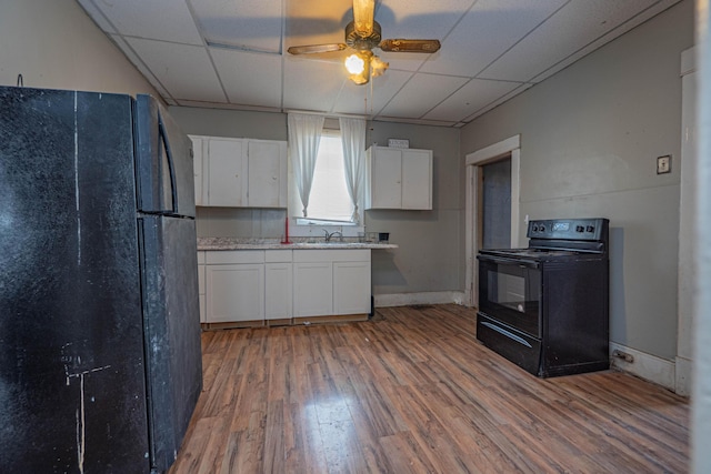 kitchen with white cabinets, wood finished floors, light countertops, a paneled ceiling, and black appliances