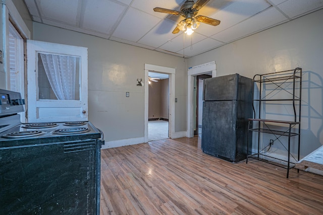 kitchen featuring ceiling fan, black appliances, a drop ceiling, and wood finished floors