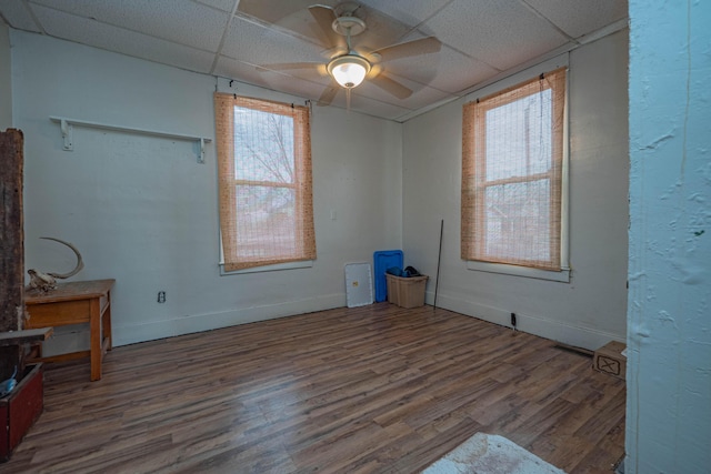 unfurnished room featuring a paneled ceiling, ceiling fan, baseboards, and wood finished floors