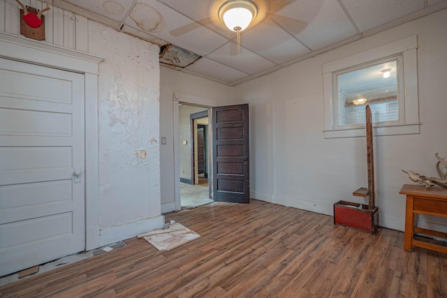 spare room with a drop ceiling, baseboards, and wood finished floors