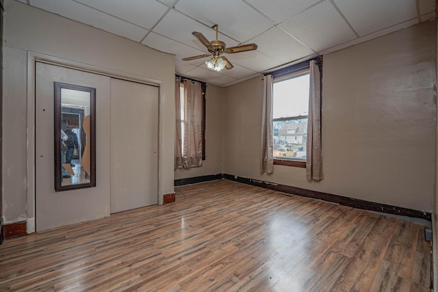 spare room with a paneled ceiling, ceiling fan, baseboards, and wood finished floors