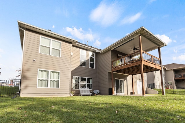 rear view of house featuring a yard, ceiling fan, a wooden deck, and fence